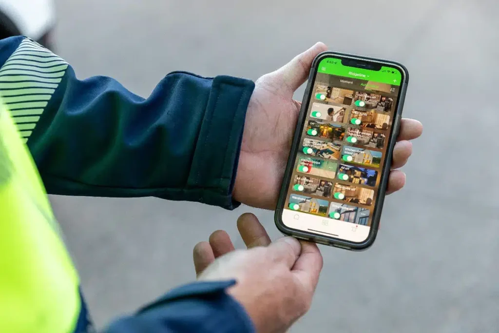 Electrician holding a phone showing a home automation app with camera feeds